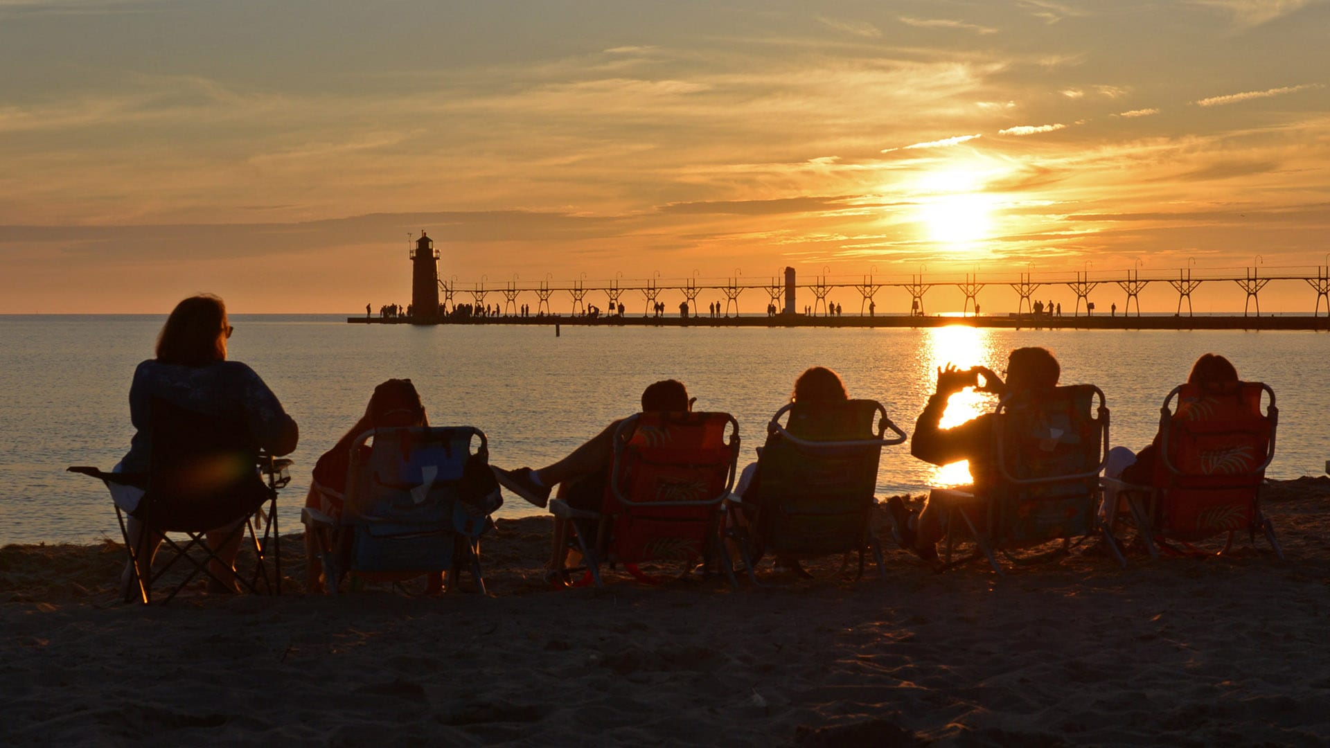 Des gens regardent le soleil se coucher près du phare historique de South Haven, dans le Michigan.